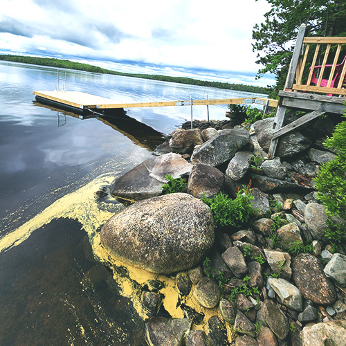Several large rocks next to a dock on the water.
